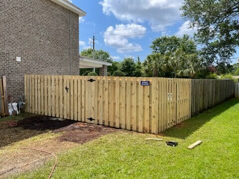 Shadowbox wood fence with double gate beside a brick home